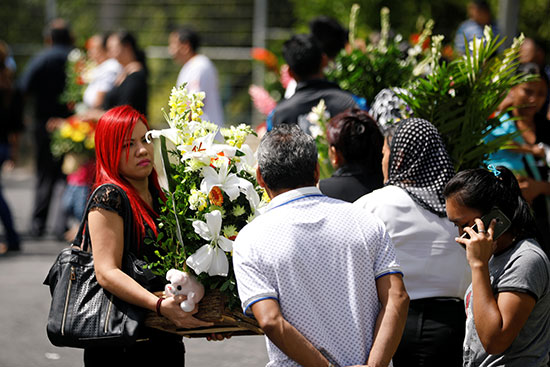المشاركون فى الجنازة يحملون اكاليل الورد