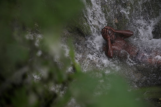أحد الحجاج مسترخيا تحت مياه الشلال