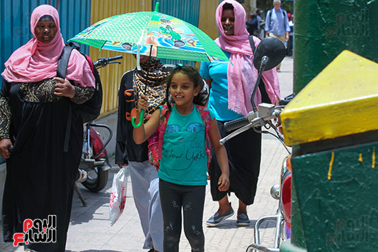 طفلة تحمل شمسية للوقاية من الحرارة في الجو