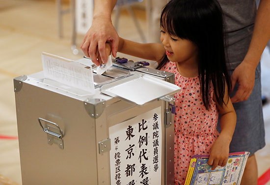 فتاة تساعد في الإدلاء بأصواتها في محطة اقتراع أثناء انتخابات مجلس الشيوخ الياباني في طوكيو