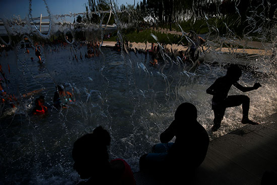 الاطفال يلهون فى الماء هربا من موجة الحر الشديدة