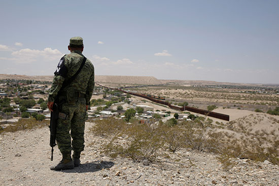 حارس امن مكسيكى ينظر للسياج الحدودى مع امريكا