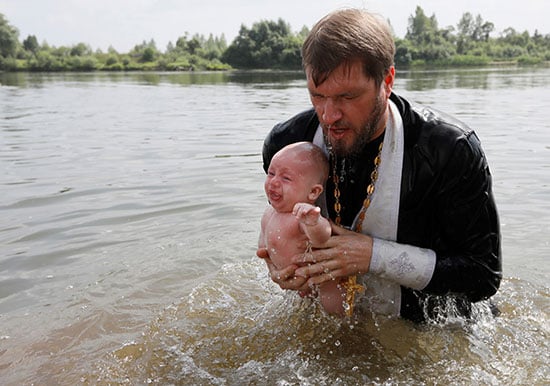 قسيس يقوم بتعميد طفل