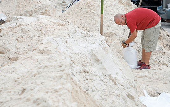 رجل يضع كيس الرمال للحماية من الاعصار