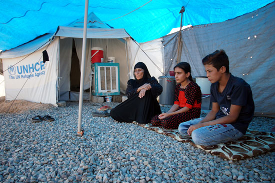امرأة-عراقية-نازحة-تجلس-مع-أبنائها-خارج-خيمتهم-في-مخيم-حسن-شام