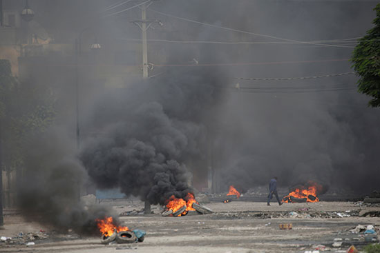رجل يمشي عبر إطارات محترقة أثناء احتجاج خارج مقر البرلمان