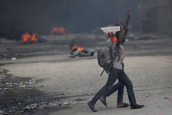 المتظاهرون يرفعون أذرعهم وهم يمشون بجوار الإطارات المحترقة
