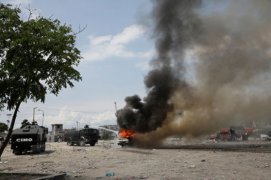 الشرطة الوطنية الهايتية تطفئ حافلة الشرطة المحترقة أثناء المظاهرة