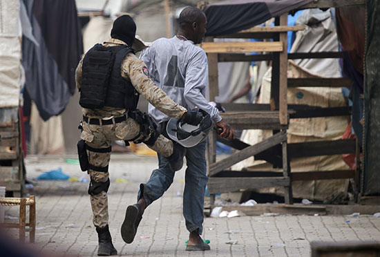 ضابط بالشرطة الوطنية الهايتية يركل رجلاً أثناء احتجاج