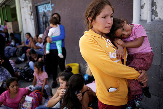 امراة مكسيكسة تحمل طفلها عند جسر عبور الحدود لأمريكا