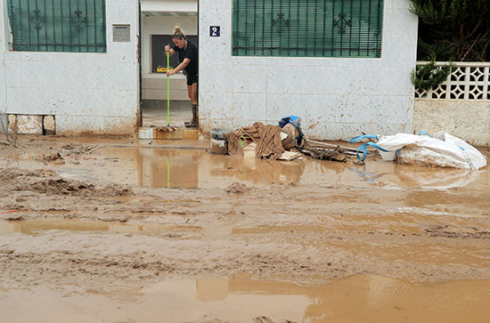 امرأة تنظف مدخلًا للمنزل بعد الفيضان الناجم عن الأمطار الغزيرة في سان خافيير ، أسبانيا