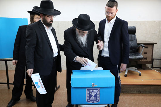 رجال يهوديون متشددون يساعدون رجلاً مسنًا في الإدلاء بصوته