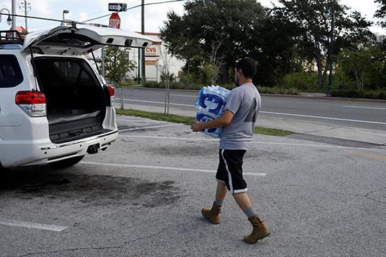 رجل يحمل زجاجات مياه قبل وصول إعصار دوريان إلى تيتوسفيل
