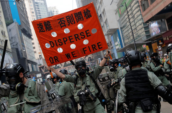 رجل-أمن-يحمل-لافتة-تدعو-لتفريق-المتظاهرين-وإما-إطلاق-النار