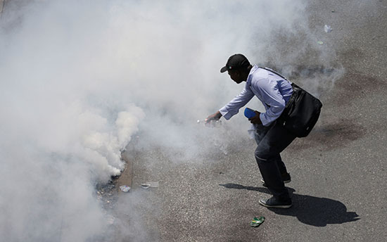 متظاهر يحاول الاقتراب من قنبلة غاز مسيل للدموع وقد انفجرت