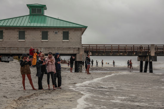 السكان المحليون يقاومون رياح إعصار دوريان أثناء التقاطهم للصور