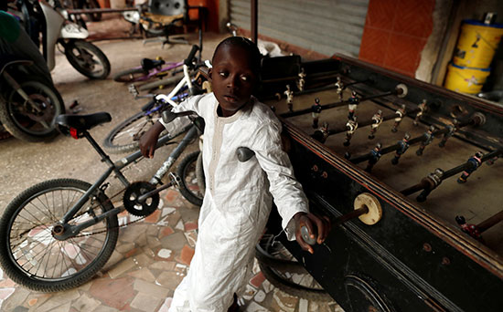 طفل يقف بجوار لعبته ودراجته فى داكار