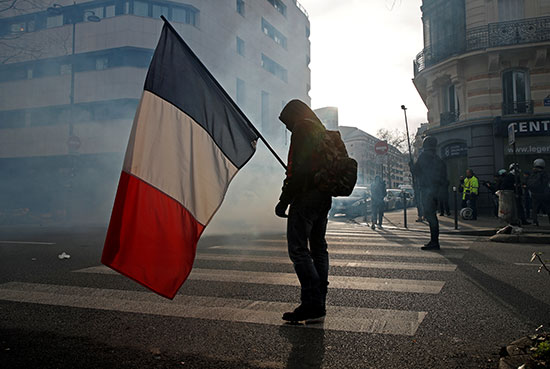 متظاهر يرفع علم فرنسا أثناء المظاهرات