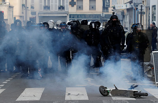 شرطة مكافحة الشغب تقف وراء سحابة من الغاز المسيل للدموع خلال مظاهرة مع أعضاء النقابات العمالية والعمال الفرنسيين