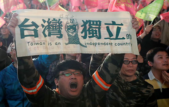 أحد مؤيدي رئيس تايوان تساي إنج ون يحمل لافتة خلال تجمع خارج مقر الحزب التقدمي الديمقراطي