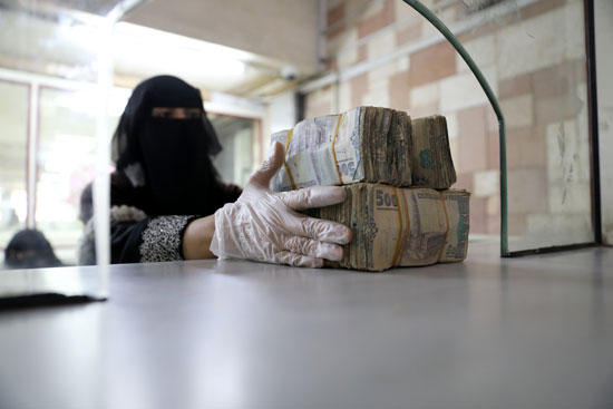 موظف يأخذ حزم من الريال اليمني في البنك المركزي اليمني