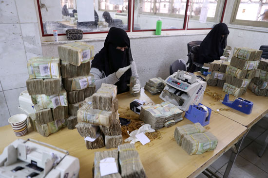 موظفون يعملون في البنك المركزي اليمني وأمامهم الحاويات النقدية