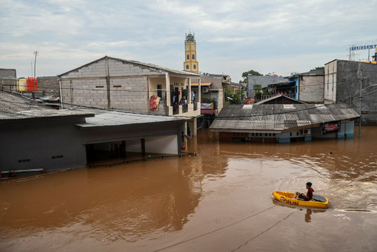 رجل يستخدم قارب قابل للنفخ أثناء الفيضانات التي ضربت جاكرتا