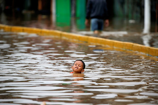 صبي يسبح في مياه الفيضان بعد هطول أمطار غزيرة في جاكرتا