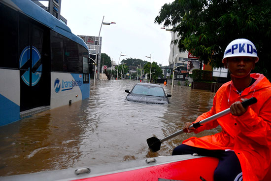 أحد حراس الأمن يستخدم قارب أثناء الفيضانات  في جاكرتا