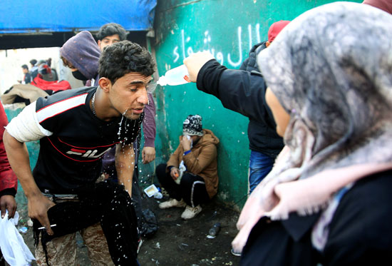 امرأة ترش الماء على وجه أحد المتظاهرين العراقيين خلال الاحتجاجات