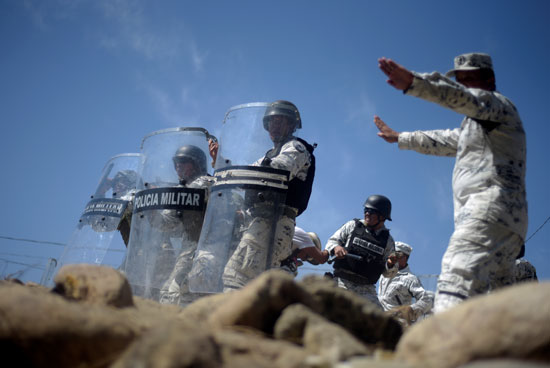 أفراد من الحرس الوطني المكسيكي يحملون دروعهم لمنع المهاجرين