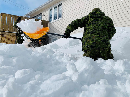 أحد أعضاء القوات الكندية يساعدون السكان في إزالة الثلوج في سانت جونز