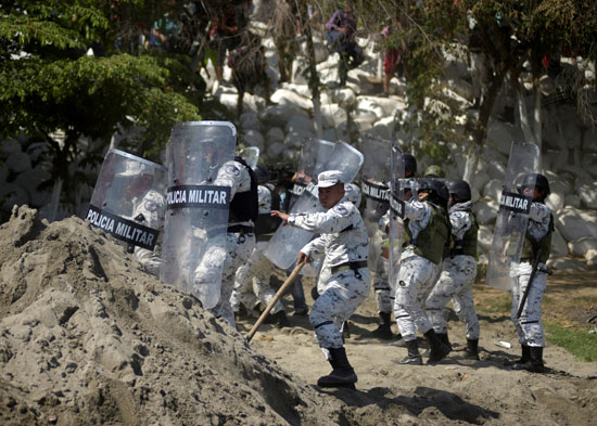 أفراد من الحرس الوطني المكسيكي يحملون دروعهم لمنع المهاجرين من دخول البلاد