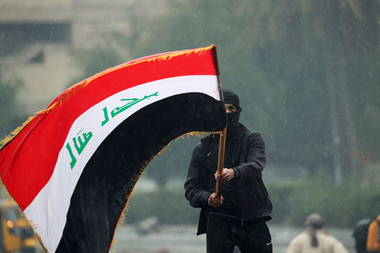 أحد المتظاهرين يرفعون علم العراق