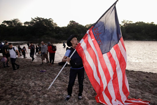 أحد المهاجرون يرفع علم أمريكا