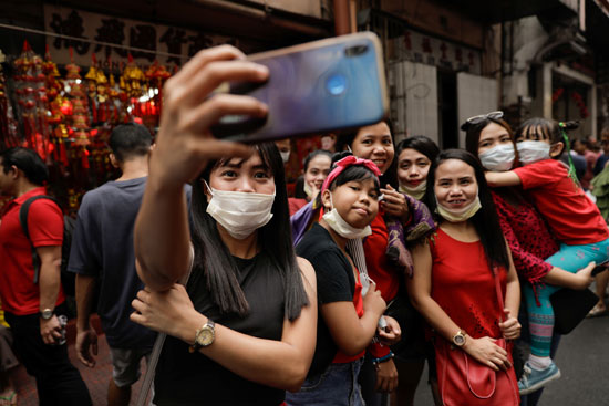 الأشخاص الذين يرتدون أقنعة واقية يأخذون صورة شخصية خلال احتفالات السنة القمرية الصينية