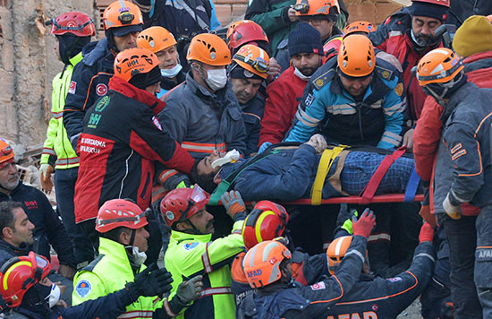 عمال الإنقاذ يحملون أحد الناجين على نقالة في موقع مبنى سكني بعد الزلزال