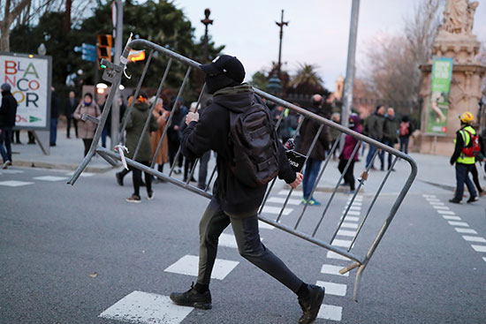 متظاهر يحمل سياجًا معدنيًا خلال مظاهرة خارج البرلمان الإقليمي في برشلونة