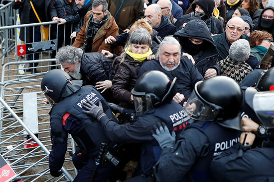 أفراد قوات الأمن يقفون حذرًا أثناء تجمع المتظاهرين خارج البرلمان الإقليمي في برشلونة