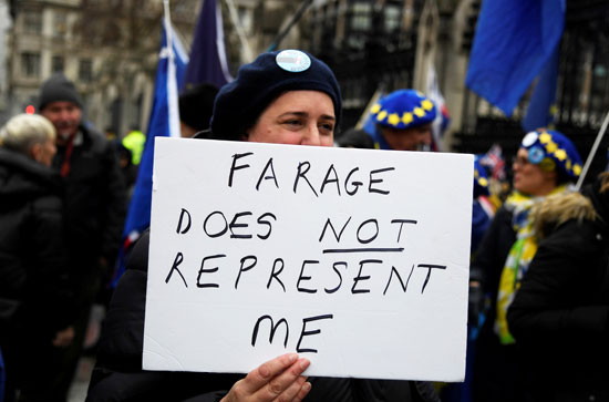 متظاهرة تحمل لافتة عليها صورة لرئيس الوزراء البريطاني بوريس جونسون