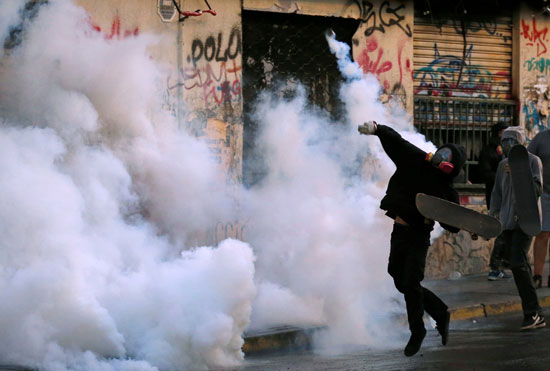 متظاهر يلقى قنبلة مسيلة للدموع على قوات الأمن