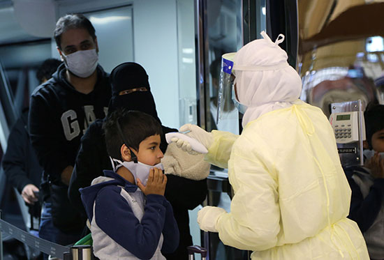 موظفة بالصحة السعودية تفحص طفل قبل دخوله البلاد