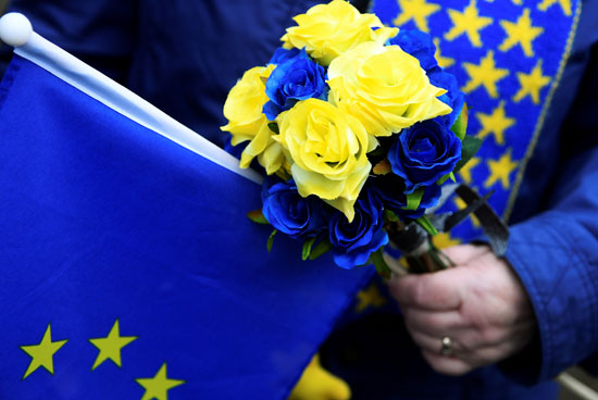 أحد المتظاهرين المناهضين لخروج بريطانيا من الاتحاد الأوروبي يحملون علم الاتحاد الأوروبي والزهور