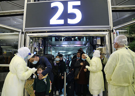 موظفو وزارة الصحة السعودية يرتدون الأقنعة أثناء فحص الركاب