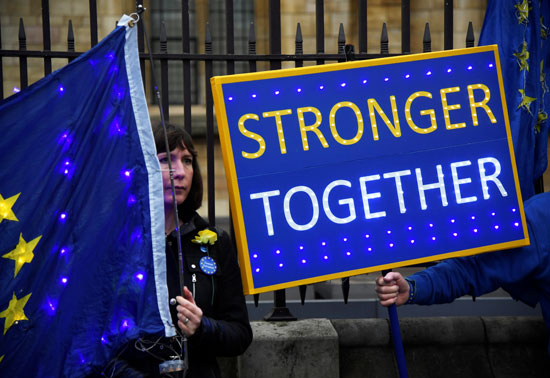 يحملون لافتة أمام مجلسي البرلمان في لندن