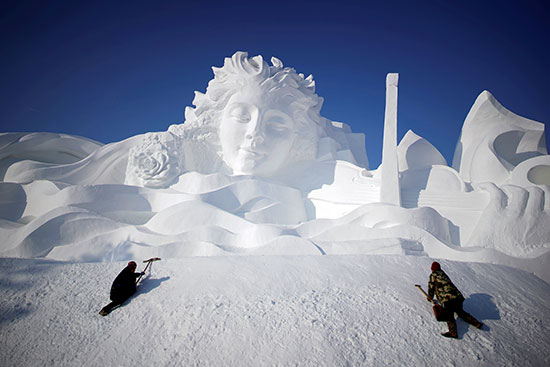 عمال يعدون تمثالًا للثلوج لمهرجان هاربين الدولي للثلج