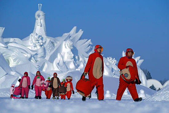 راقصون يرتدون أزياء يغادرون بعد الانتهاء من أدائهم لمهرجان هاربين الدولي للثلج