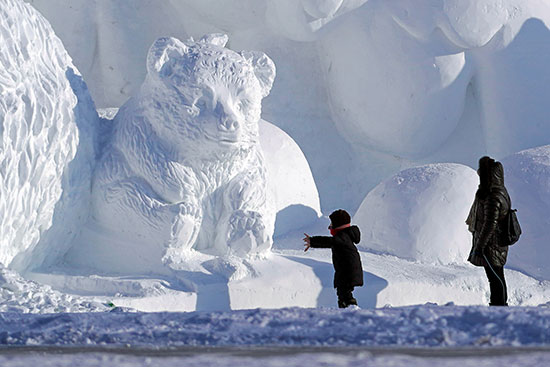 يزور الناس تمثالًا ثلجيًا تم إعداده لمهرجان هاربين الدولي للثلج