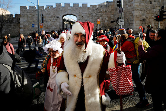 رجل يرتدى زى سانتا كلوز يمشى خارج المدينة القديمة بالقدس