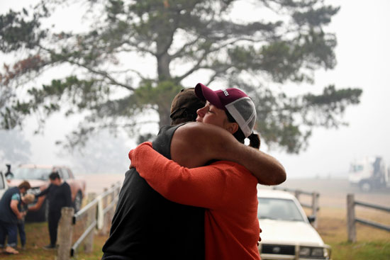 رجل وزوجته يحتضنون بعضهما بعد إحتراق منزلهما جراء حرائق أستراليا